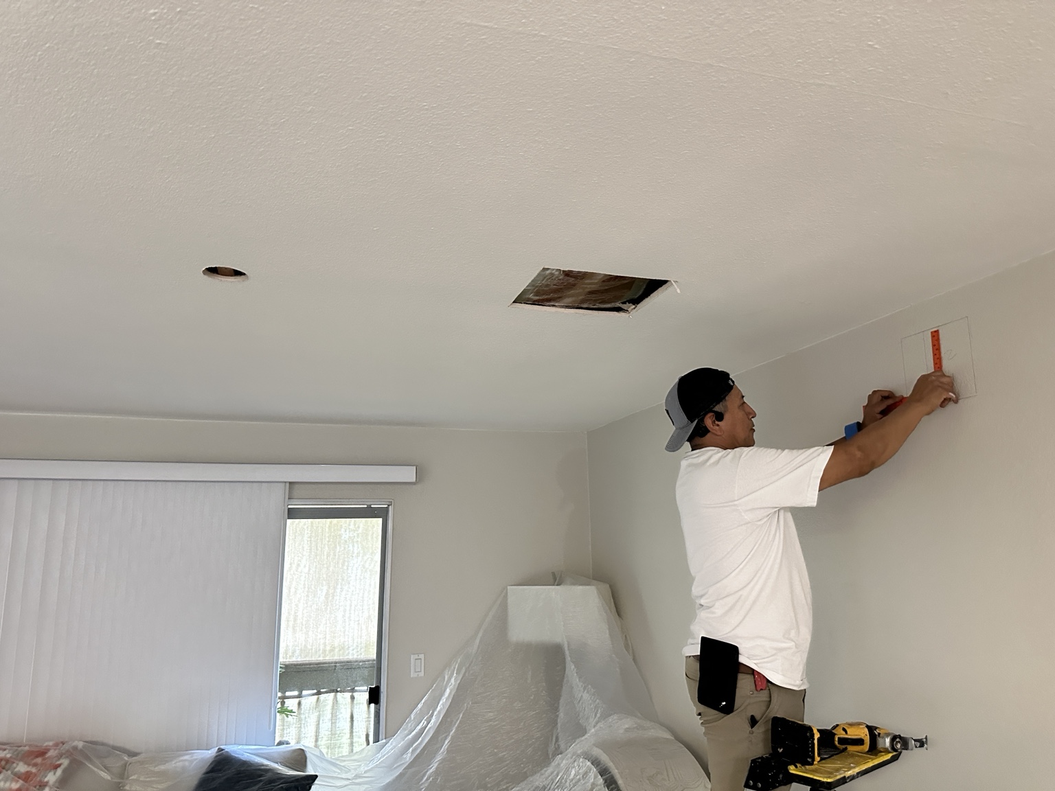 Technician marking a wall during a ceiling fan installation