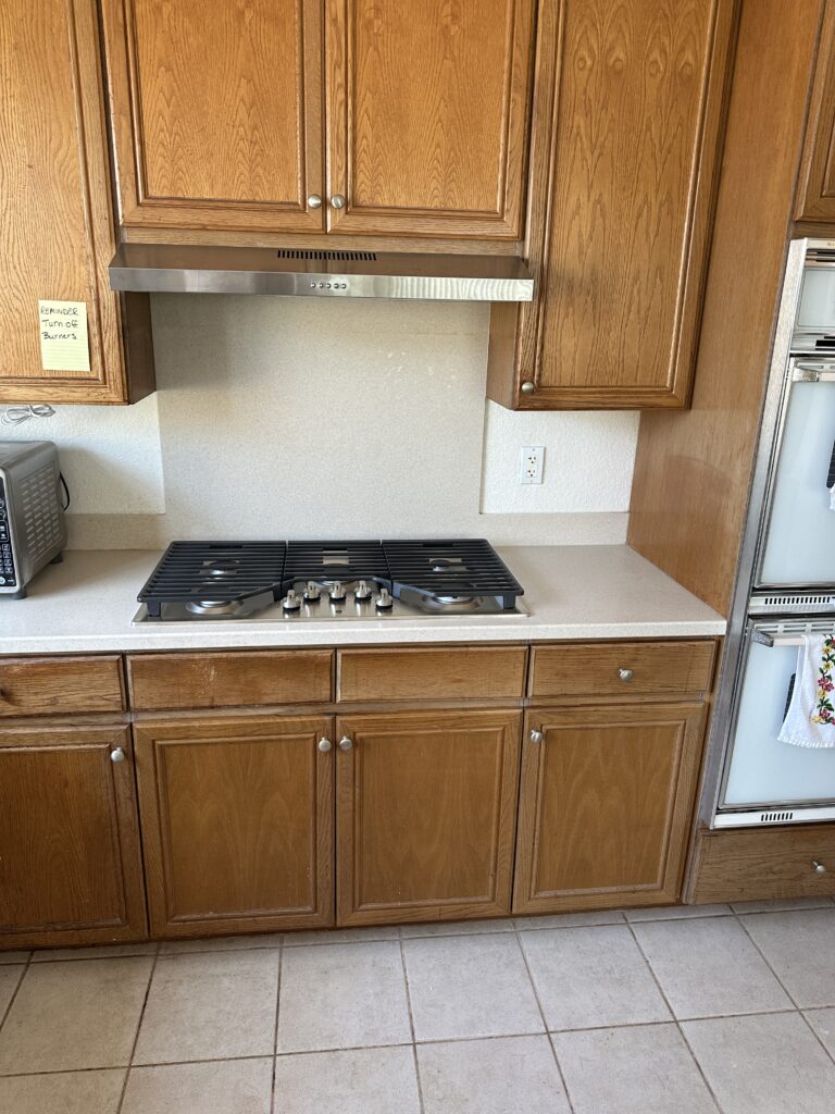 Newly installed cooktop and stainless steel exhaust hood in a kitchen