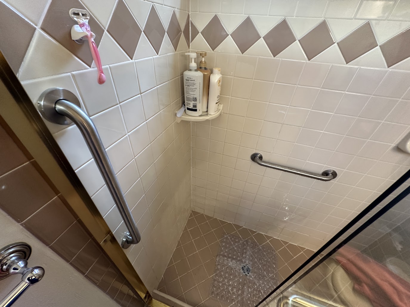 Two stainless steel grab bars installed in a tiled shower, one at the entry and one on the back wall