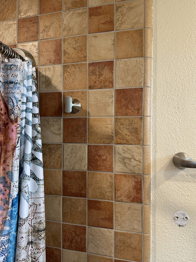 Metal towel hook mounted on the tiled wall beside an Oceanside shower