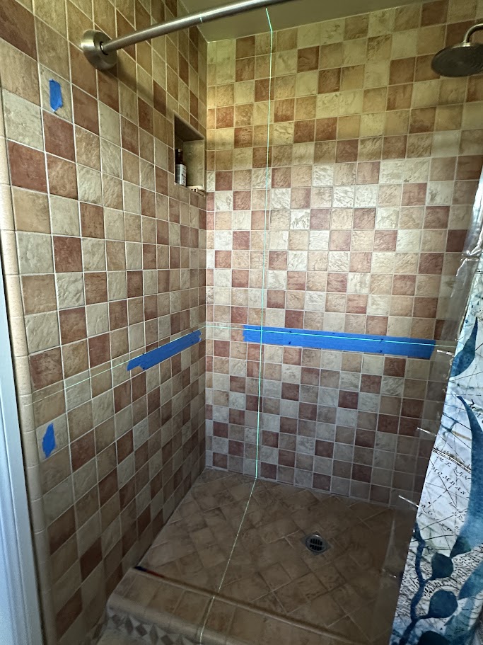 Blue tape and laser lines marking proposed grab bar locations in an Oceanside tiled shower